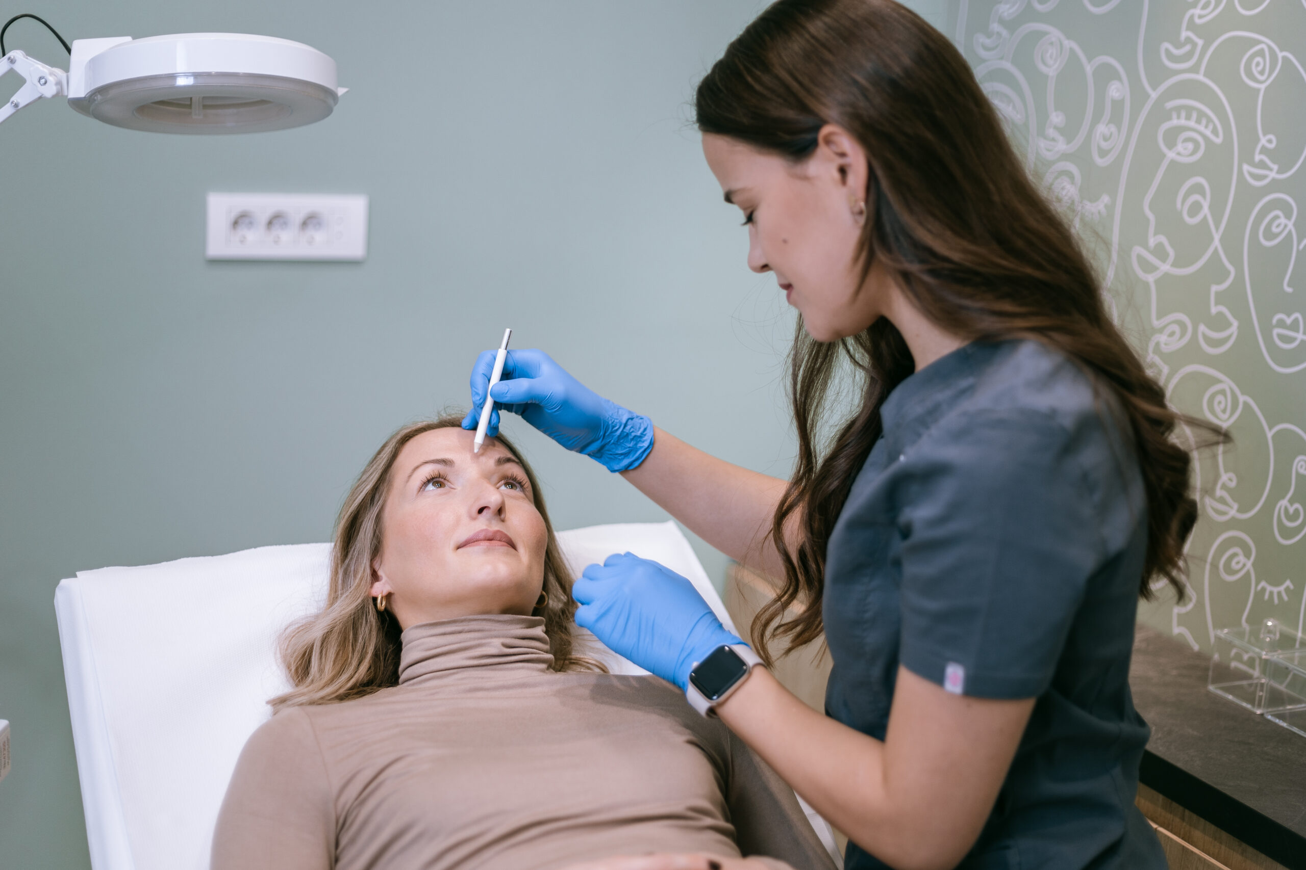 doktorica iscrtava belom olovkom linije po licu klijenta